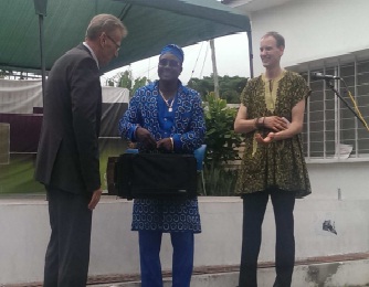 Ambassador Ruediger John hands over instrument to leader of the Kopeyia Brass Band. With them is Mr. Jo Junghanss